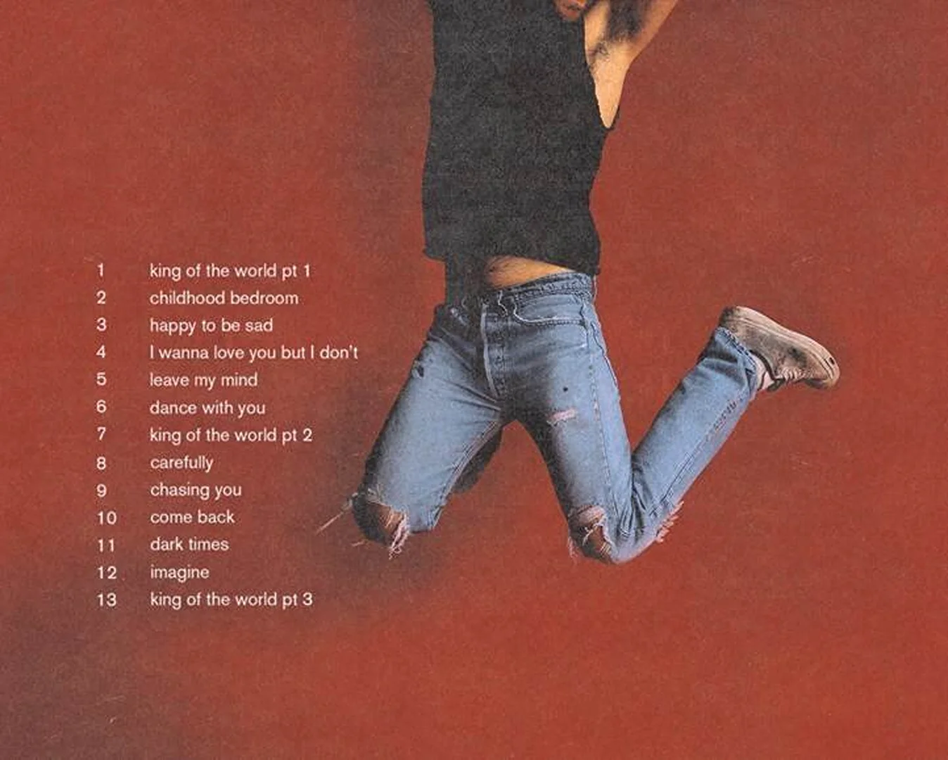 An adult male with dark hair jumping mid-air wearing a tank top, ripped jeans, and sneakers against a solid red background with track list.