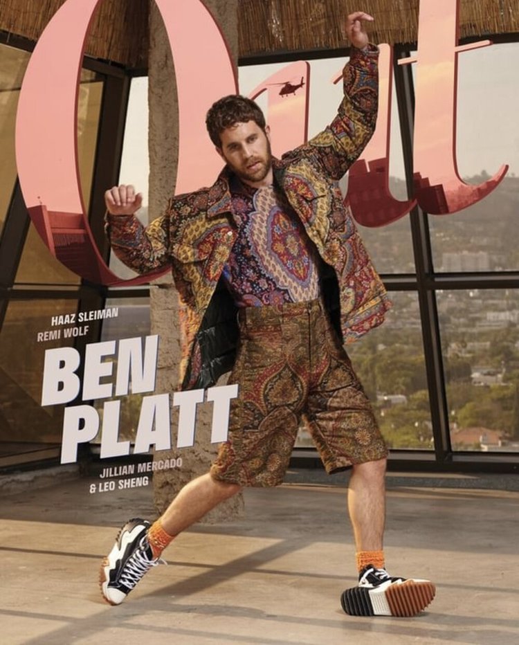 Ben Platt poses outdoors in patterned jacket and shorts, accessorized with color-block sneakers, for a vibrant fashion editorial.