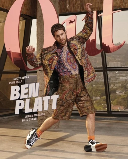 Ben Platt poses outdoors in patterned jacket and shorts, accessorized with color-block sneakers, for a vibrant fashion editorial.