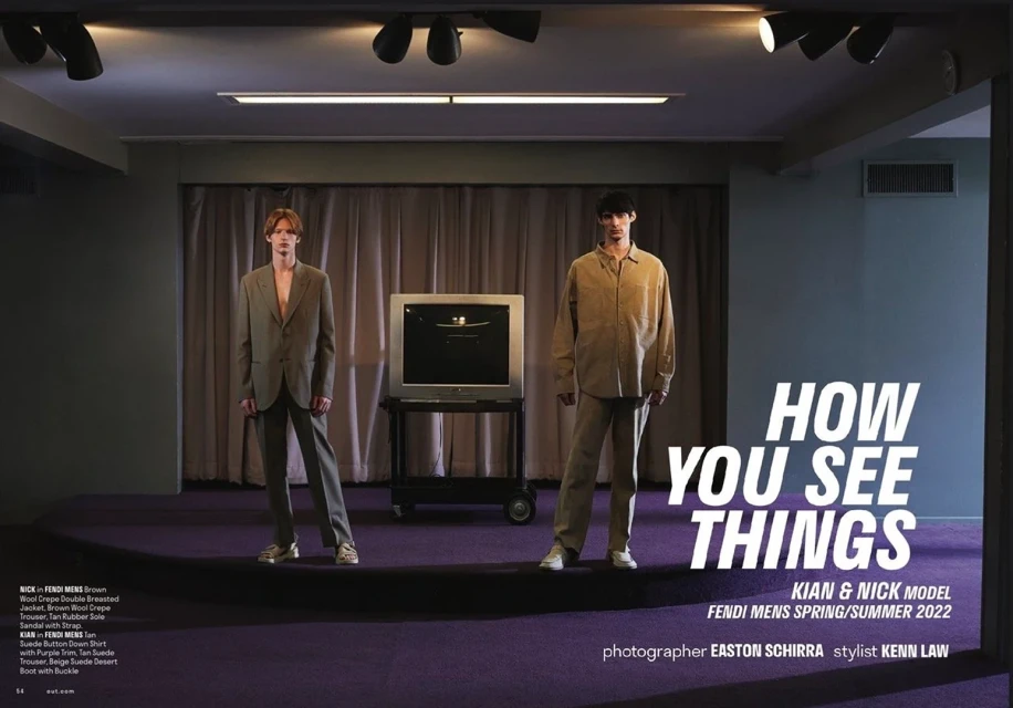 Two adult male models pose in a studio setting, displaying Fendi menswear from the Spring/Summer 2022 collection, with an old television set.