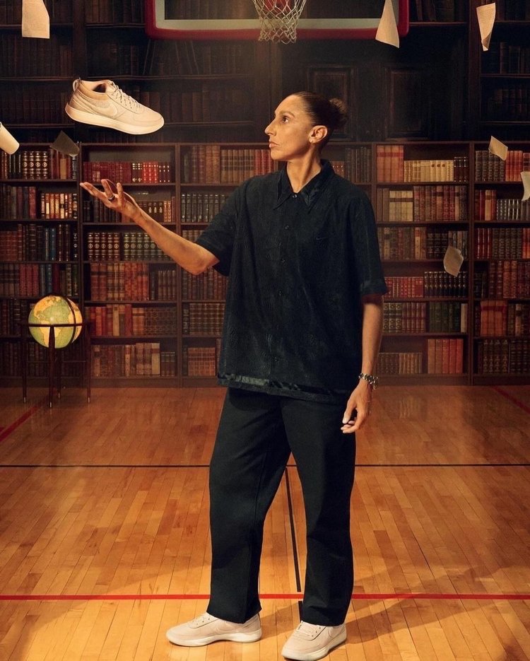 Professional female basketball player wearing casual clothing indoors, juggling a sneaker in the air inside of a basketball court library.