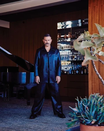 Man wearing a dark leather jacket and matching trousers standing inside a stylish lounge interior styled by Kenn Law.