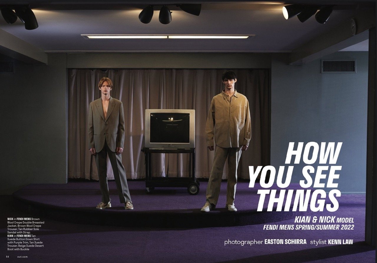 Two male models showcase Fendi menswear spring/summer 2022 in a photo studio setting with a retro television, promoting fashion editorial style.