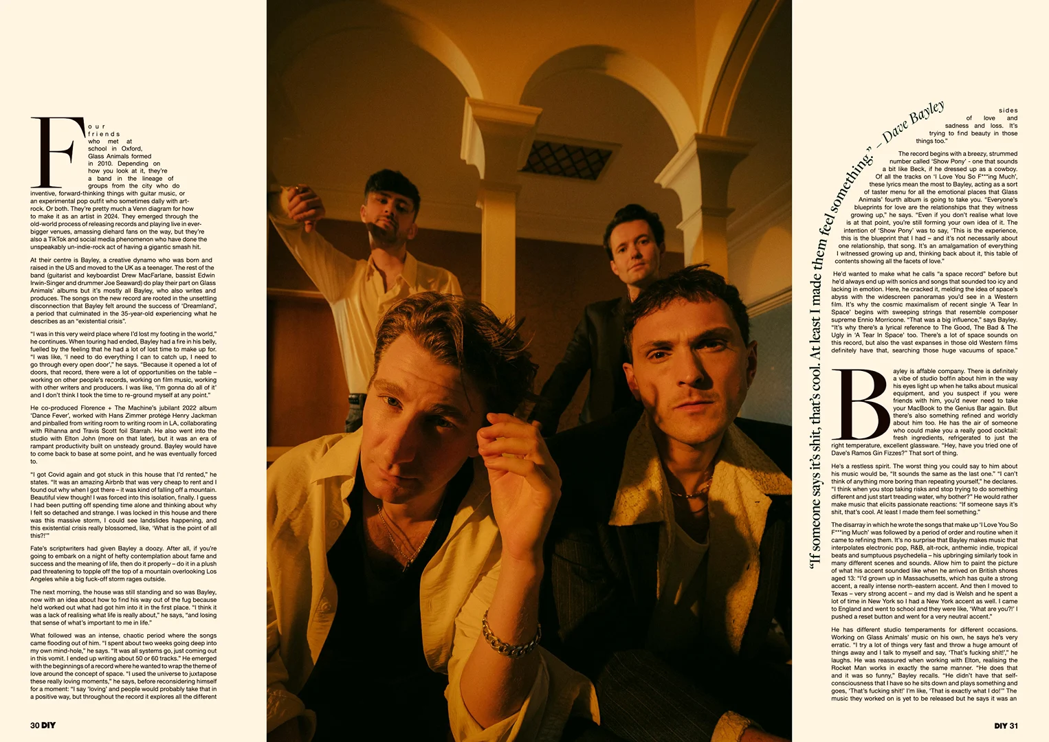 Group portrait of four young adult men indoors with warm lighting, posing in fashionable attire, for a music-related editorial piece.