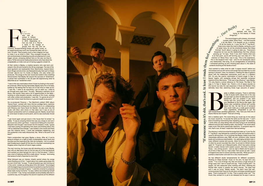 Group portrait of four young adult men indoors with warm lighting, posing in fashionable attire, for a music-related editorial piece.