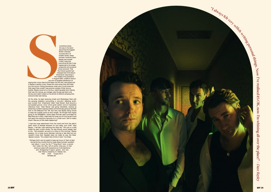 Band members from The Oxford, a British indie rock band, stand together in a dimly lit hallway with warm, green lighting for a promotional shoot.