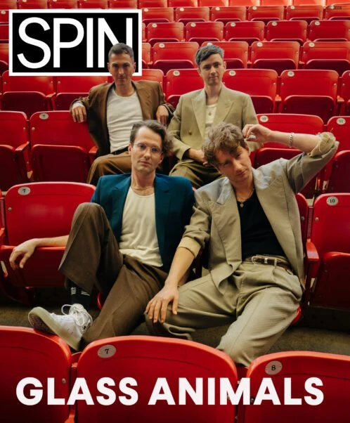 The band Glass Animals poses in red theatre seats, promoting SPIN magazine; medium shot, eye-level angle, neutral facial expressions.