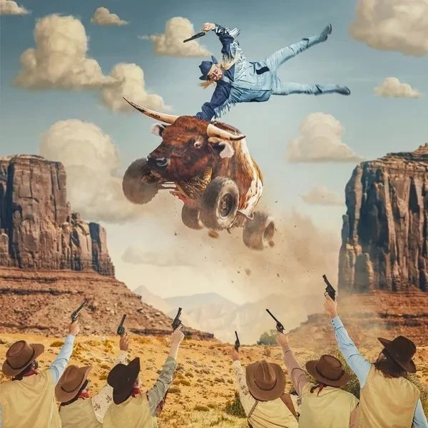 A bull with wheels jumps over a desert landscape as a cowboy flies through the air and a group of people point guns upward.