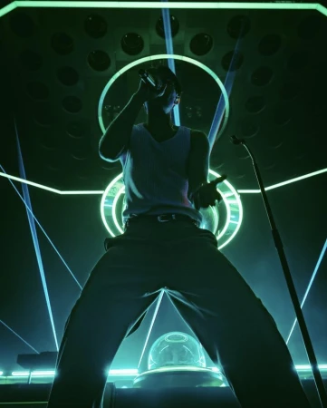 Low angle view of a man singing into a microphone on stage with neon lights. He is wearing a tank top and trousers.