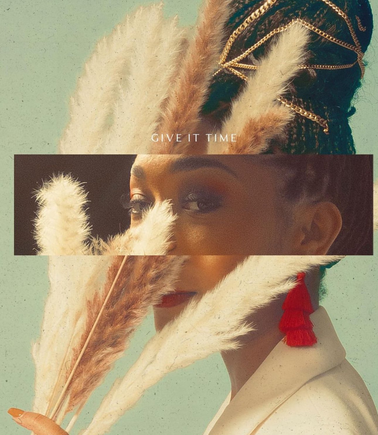 Eye-level shot of a stylish young Black woman's face partially obscured by decorative grass, featuring a striking gold headpiece.