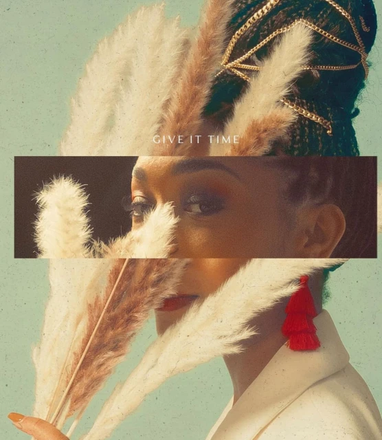 Eye-level shot of a stylish young Black woman's face partially obscured by decorative grass, featuring a striking gold headpiece.