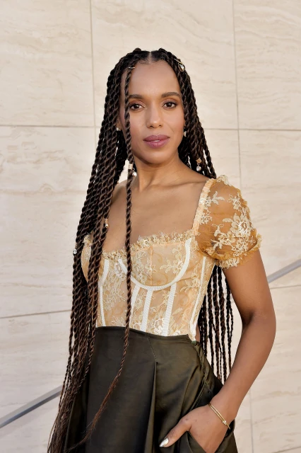 Portrait of Kerry Washington in a tan corset top and dark olive skirt against a neutral wall, showcasing a blend of elegance and style.