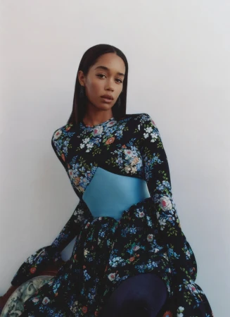 Woman with long dark hair wearing a black floral long-sleeve dress with a blue satin cummerbund.
