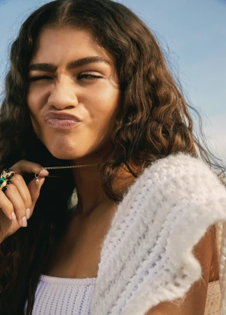 Close-up portrait of Zendaya making a playful facial expression while wearing a textured white knitted top
