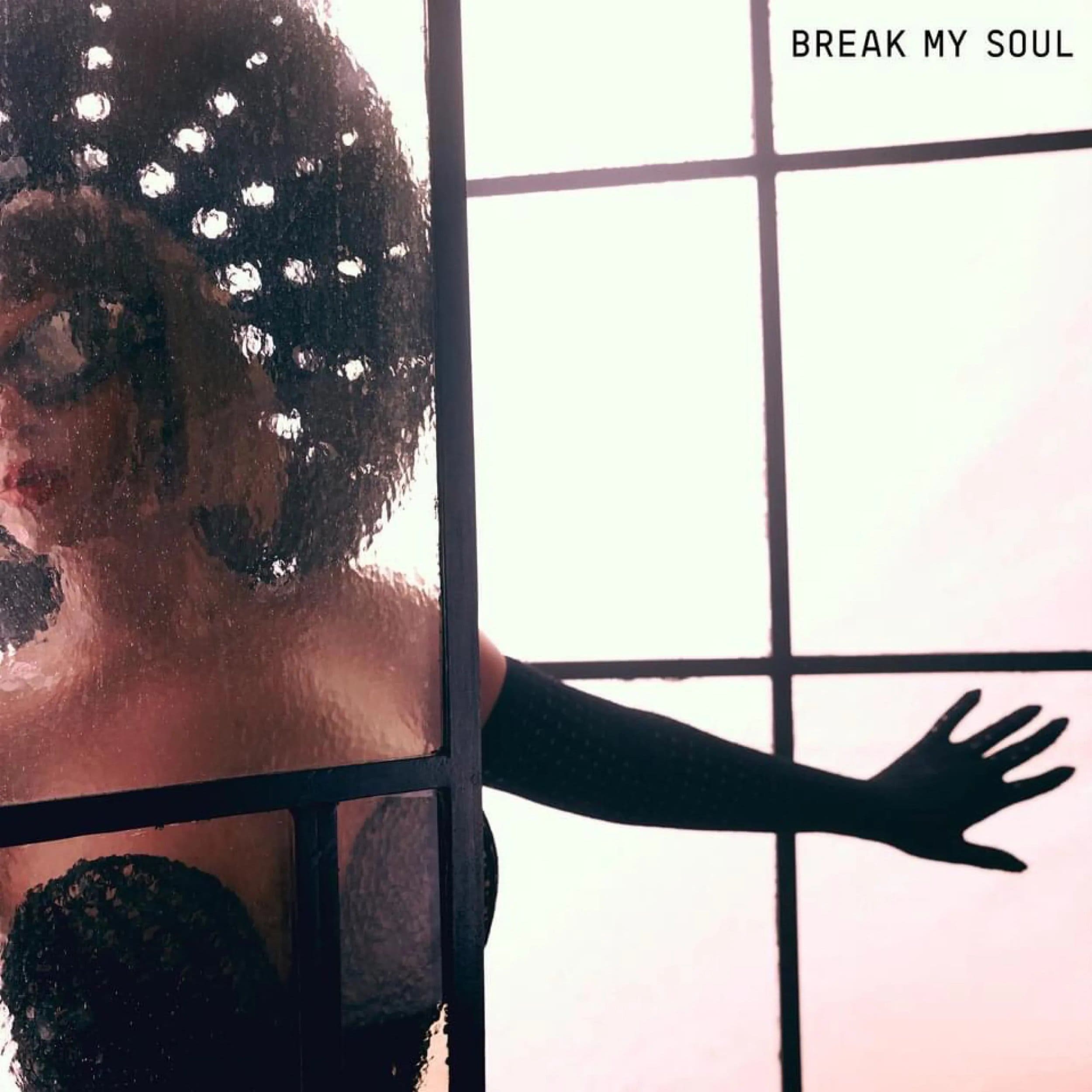 Woman with an afro, behind textured glass next to a window, wearing a black top and gloves, arm outstretched, red lips, album cover. 