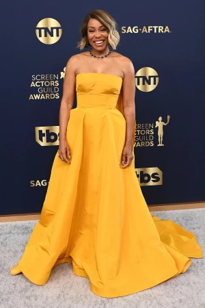 Woman on red carpet in mustard-yellow strapless gown at Screen Actors Guild Awards with SAG-AFTRA and TBS logos in background.