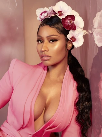 Close-up portrait of an adult woman with dark hair wearing a pink blazer and an orchid flower crown, posing against a pink backdrop.