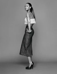 Black and white portrait of Beyonce standing in profile wearing a crop top and midi skirt with hair styled in a ponytail