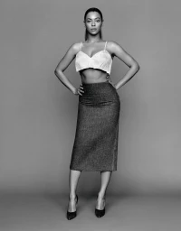 Full-length black and white portrait of Beyoncé posing with hands on hips wearing a cropped top and midi skirt
