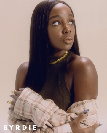 Black woman with long straight hair wearing a dark sleeveless top and a plaid jacket, styled by Kinsey Ranee.