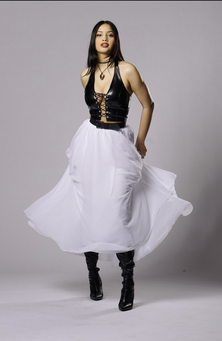 Model wearing a black lace-up halter top and a long white skirt against a plain grey backdrop