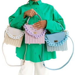 Model wearing vibrant green shirt holding three woven handbags with chunky chain straps against a bright white background