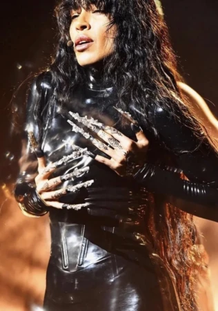 Performer in glossy black latex catsuit with elaborate textured nails styled by Kirsty Stewart