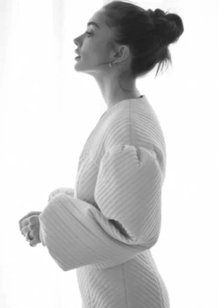 Profile view of a woman with her hair in a bun wearing a quilted dress, styled by Kirsty Stewart against a bright background.