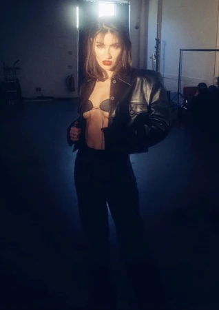 Model in black leather jacket and dark pants standing in an industrial studio styled by Kirsty Stewart