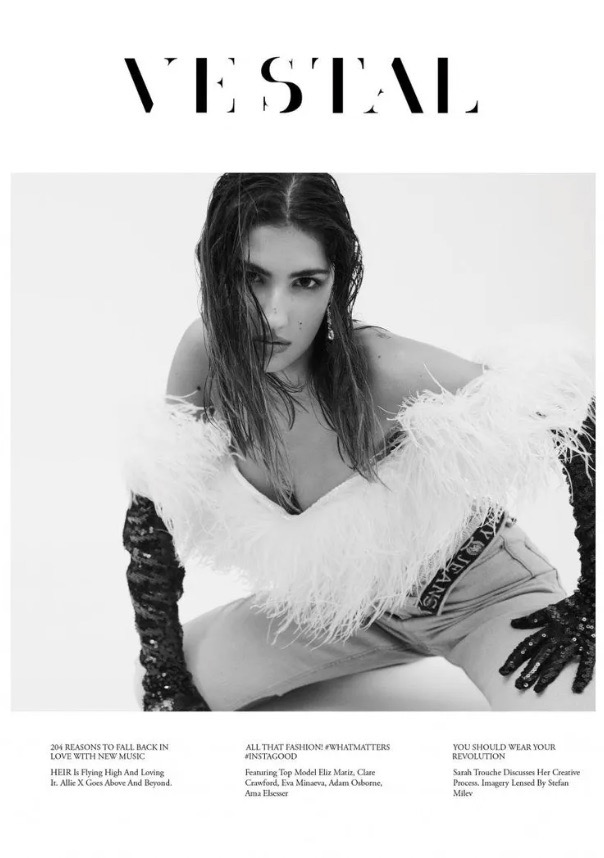 Black and white fashion magazine cover with a woman in an off-the-shoulder feather top, jeans, and long gloves.