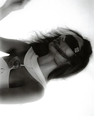 Black and white editorial portrait of a woman wearing a blindfold and large pendant necklace, styled by Kirsty Stewart