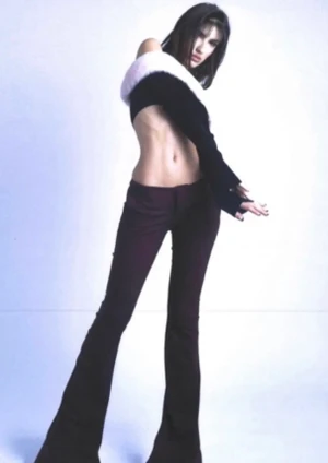 Model wearing dark trousers and a black cropped top against a seamless white background, styled by Kirsty Stewart