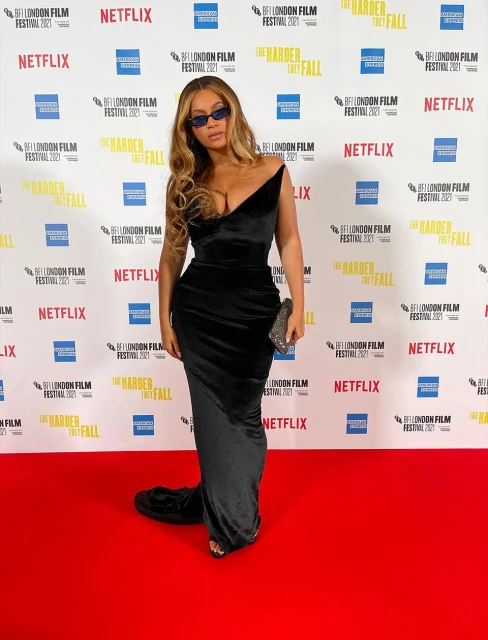 Beyonce attends the BFI London Film Festival 2021, wearing a black velvet dress, posing on the red carpet in front of a branded backdrop.