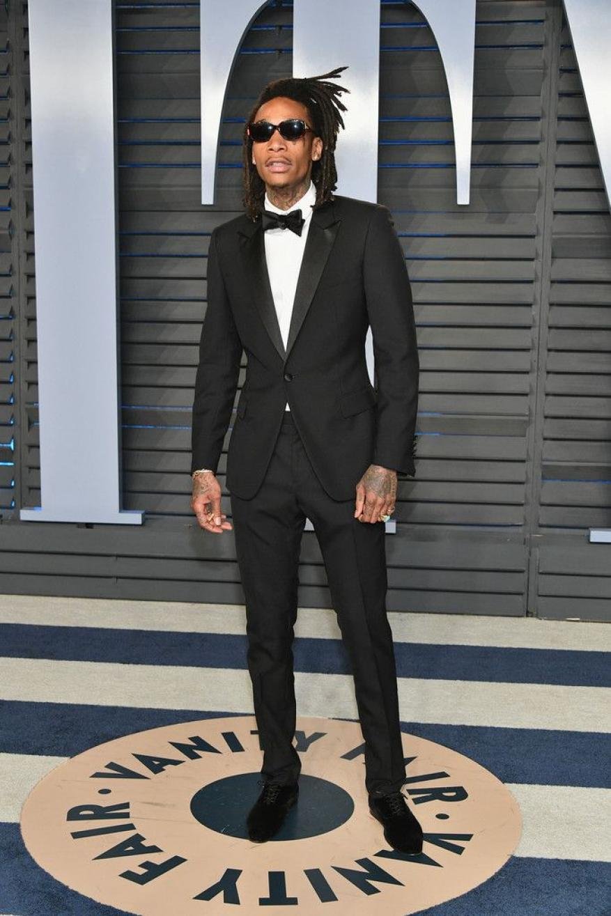 Wiz Khalifa in a black tuxedo and sunglasses poses on a striped circle for the Vanity Fair Oscar party red carpet.