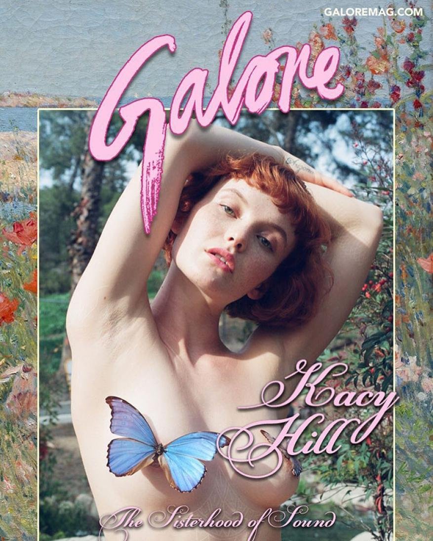 Portrait of a redhead woman with a butterfly covering her chest, posing outdoors with artistic floral backgrounds and Galore magazine logo.