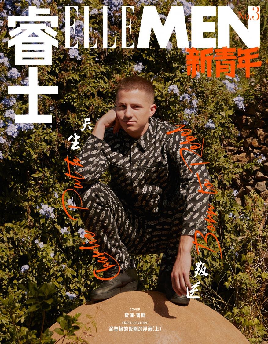 Elle Men magazine cover featuring a male model in a patterned jumpsuit crouching outdoors with a floral background in warm lighting.