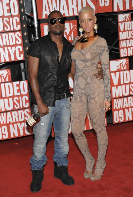 Kanye West and Amber Rose pose on the red carpet at the MTV Video Music Awards 2009, standing closely together with branded backdrop.