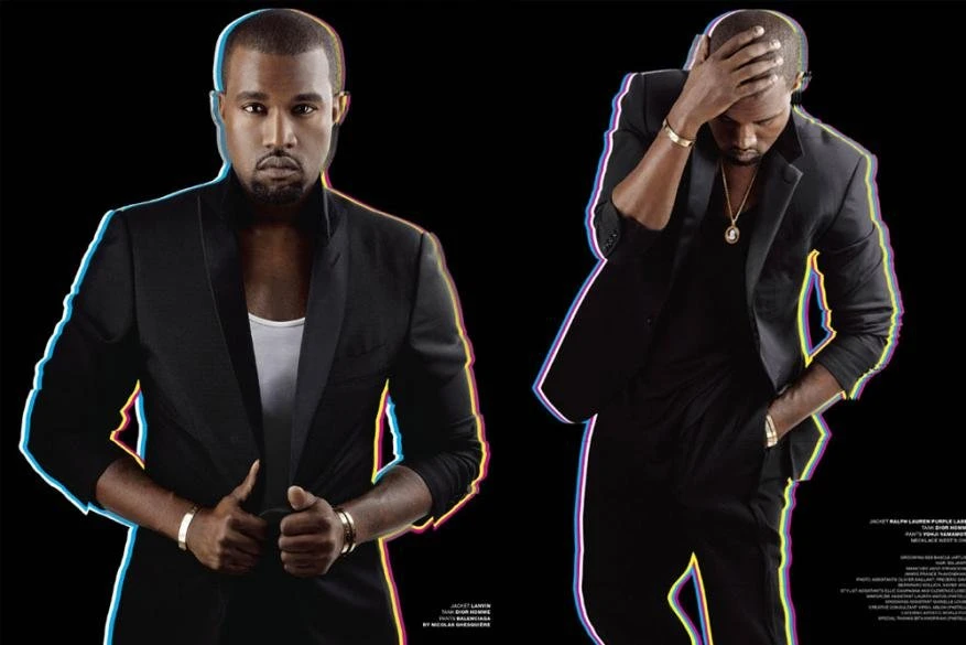 Two adult males wearing black suits pose in a studio with a black background, showcasing formal wear and fashion for an editorial photoshoot.