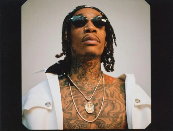 Portrait of Wiz Khalifa wearing sunglasses and a patterned headscarf with heavy neck and chest tattoos