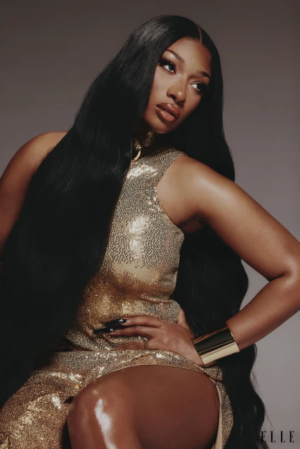 Portrait of a Black woman with long black hair and a golden sequined dress. She poses in a studio setting with elegant lighting.