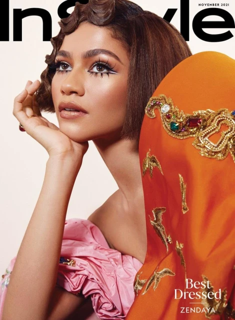 Zendaya poses in a shoulder-up shot for InStyle magazine cover; she is wearing an orange dress with gold embroidery and pink dress.