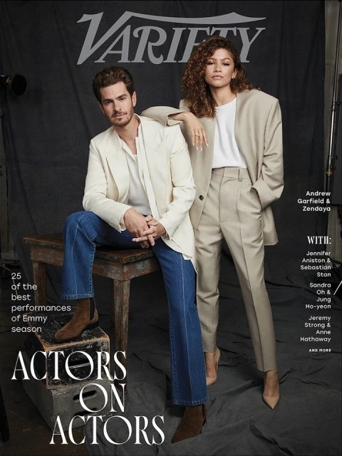 Magazine cover featuring Andrew Garfield and Zendaya. The actors are posing in stylish outfits in front of a dark backdrop.