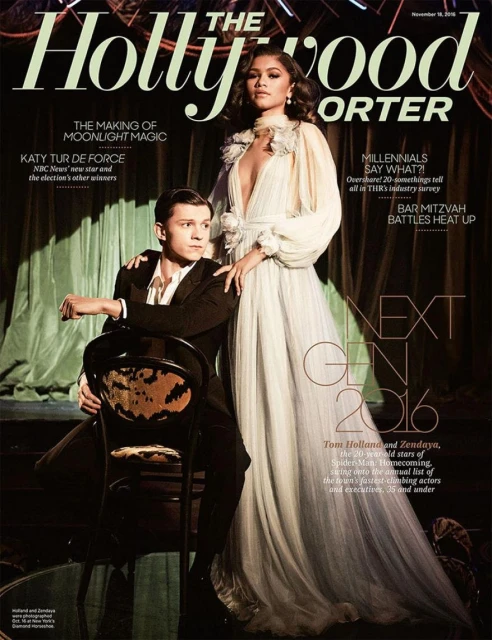 The Hollywood Reporter cover with Zendaya in long gown standing next to Tom Holland sitting on chair in a dark, elegant setting.