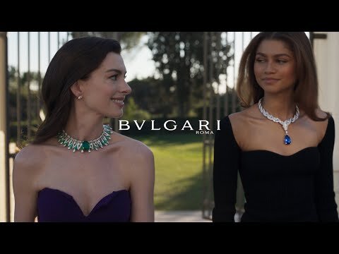 Anne Hathaway and Zendaya pose wearing Bvlgari jewelry; both women wear strapless dresses in an outdoor setting.
