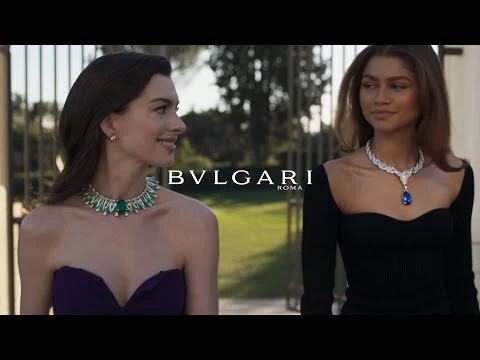 Anne Hathaway and Zendaya pose wearing Bvlgari jewelry; both women wear strapless dresses in an outdoor setting. 