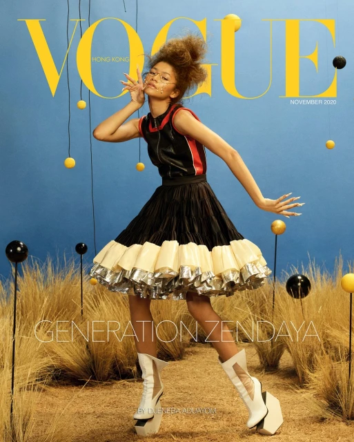 Magazine cover featuring Zendaya in a black and white dress against a blue backdrop with hanging spheres and tall grass.