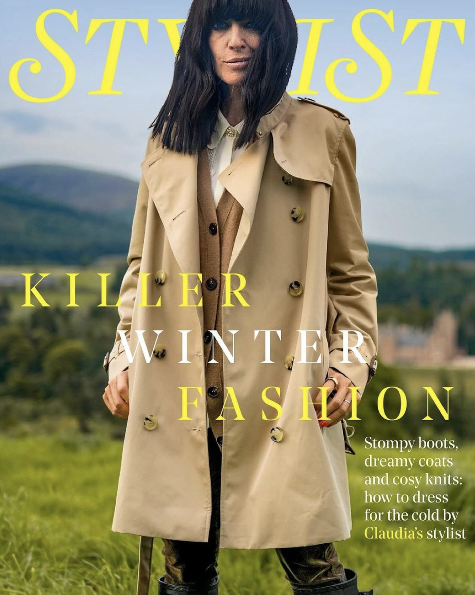 Fashion magazine cover featuring a female model wearing a trench coat, standing in a field with a castle in the background.
