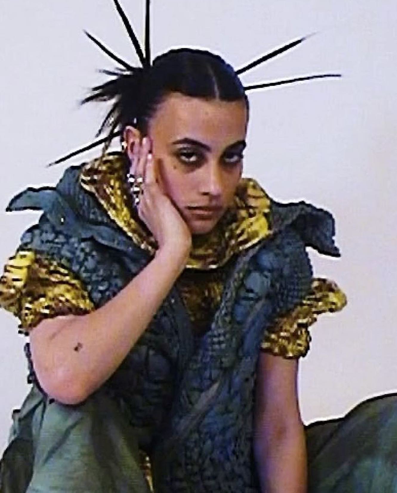 Young adult posing with a futuristic fashion top with spikey hair in a studio setting.