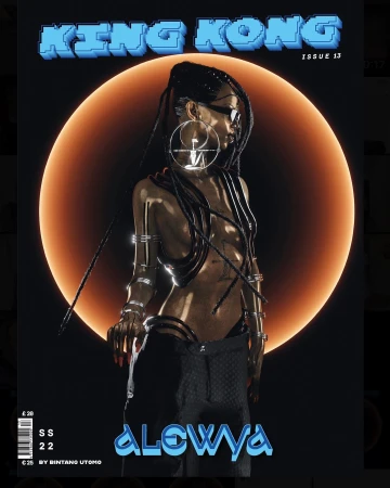 Magazine cover featuring a woman with braids, stylized eye-wear and futuristic jewellery, posing in front of an orange circle.