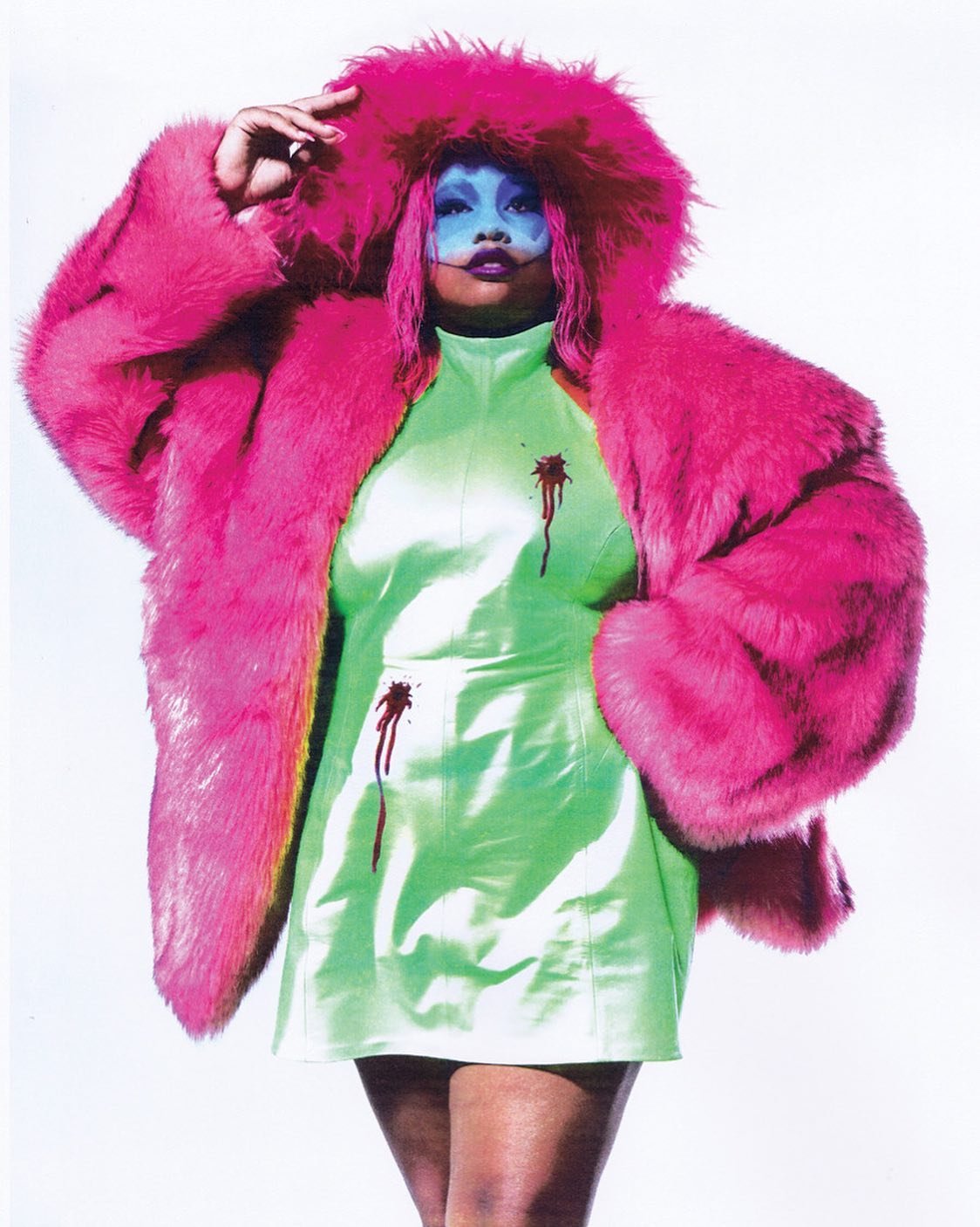 Portrait of a person with blue face paint wearing a lime green dress and a pink fur coat with dark red streaks, on white background.
